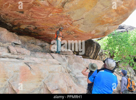 Aboriginal guide pointing out artwork in a rock art gallery on Injalak Hill, Arnhem Land, Northern Territory, Australia Stock Photo