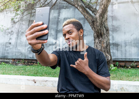 Close up of attractive dark-skinned man making selfie on mobile phone. Stock Photo