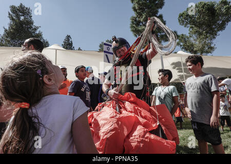 Jerusalem, Israel. 27th September, 2018. Opening the Jerusalem Parade, skydivers from the Israeli Association for Parachuting perform an exhibition landing in Sacher Park in celebration of the city's 50th anniversary of reunification. One jumper miscalculated his approach and landed among the spectators. There were no injuries. Credit: Nir Alon/Alamy Live News Stock Photo