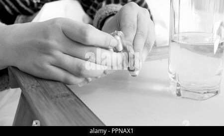 Black and white image of female hands unpacking pills Stock Photo