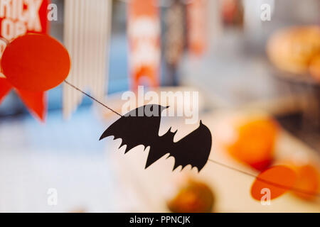 Little black bat made out of paper hanging above the Halloween celebration table Stock Photo