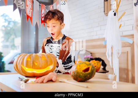 Schoolboy wearing skeleton costume for Halloween standing near pumpkin Stock Photo