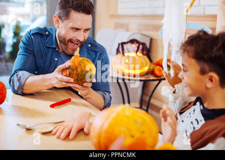 Funny loving father playing tricks with his cute son wearing skeleton costume Stock Photo