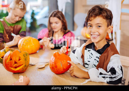 Boy wearing skeleton costume for Halloween feeling amazing coloring pumpkins Stock Photo