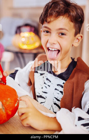 Cute boy wearing skeleton costume for Halloween party coloring pumpkin Stock Photo