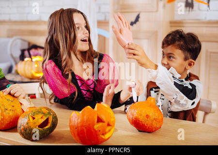 Cute boy wearing skeleton Halloween costume plating tricks with older sister Stock Photo