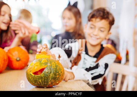 Smiling funny boy wearing skeleton costume looking at Halloween pumpkin Stock Photo