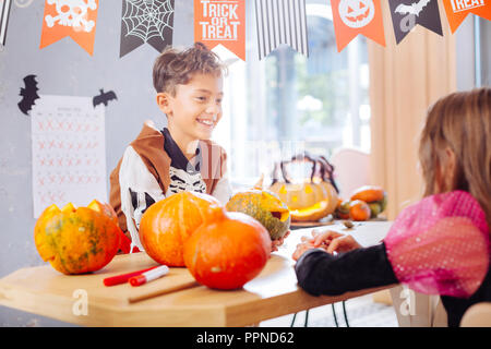 Beaming funny boy wearing Halloween skeleton costume talking to his friend Stock Photo