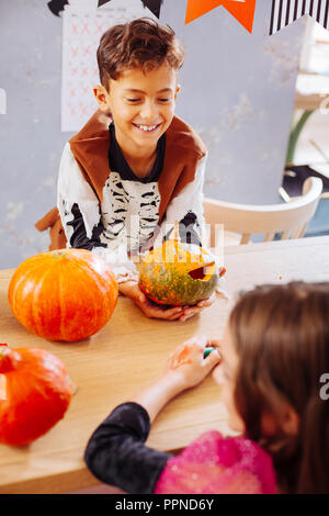 Curly dark-haired smiling boy wearing skeleton costume for Halloween Stock Photo