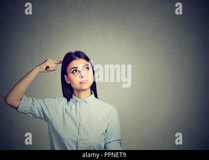 Young puzzled brunette woman scratching head in perplexion looking away Stock Photo