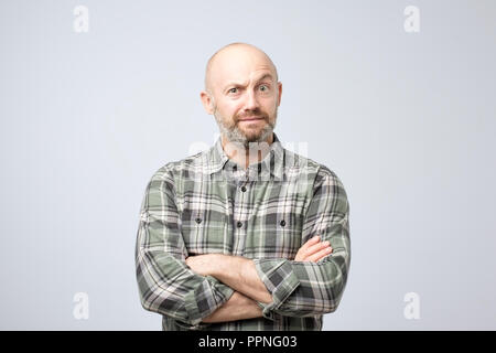 grumpy mature european man posing in studio with arms folded, feeling insulted while having quarrel with his girlfriend Stock Photo