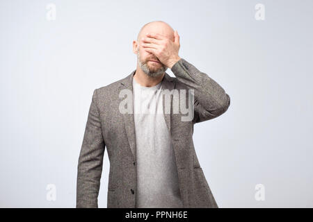 Portrait a disappointed mature man covering his face with his hand. Stock Photo