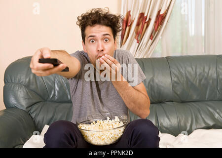 Man with beer and popcorn watching TV at home Stock Photo