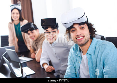 group of multiethnic business partners with virtual reality headsets at table with laptops in modern office Stock Photo