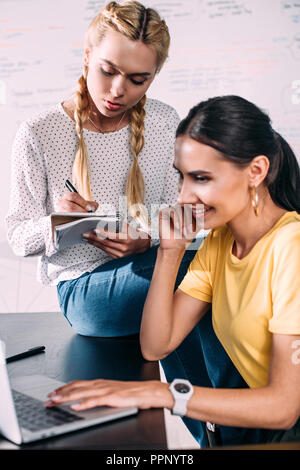 two businesswomen working with textbook and laptop in modern office Stock Photo