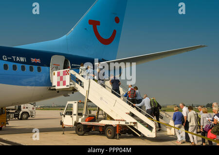 Passengers climbing the stairs to board their TUI holiday jet via the rear door. Stock Photo