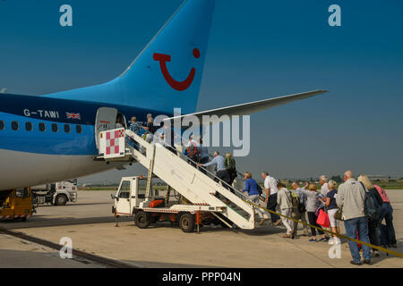 Passengers climbing the stairs to board their TUI holiday jet via the rear door. Stock Photo