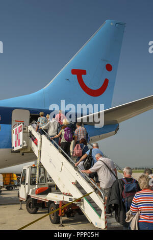 Passengers climbing the stairs to board their TUI holiday jet via the rear door. Stock Photo