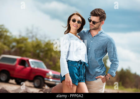 beautiful smiling couple of travelers hugging, red car on background Stock Photo