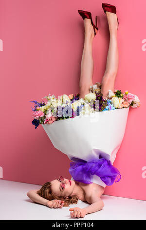beautiful young woman with fresh flowers in dress on pink, upside down view Stock Photo