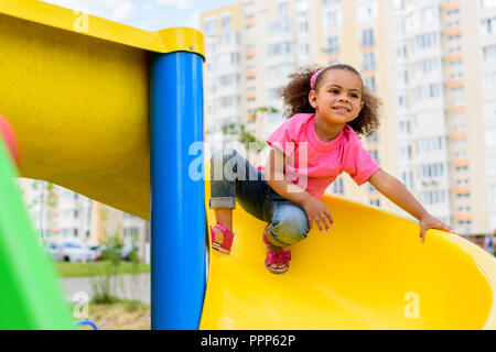 Cute little african american boy sliding down the slide, kid