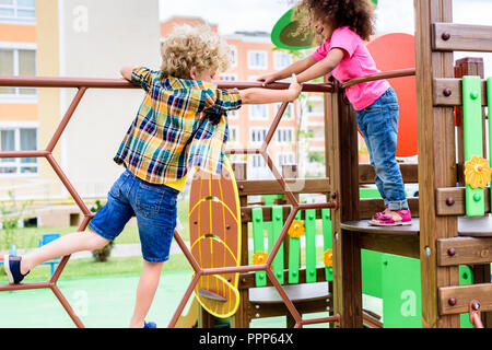 two multiethnic little kids climbing and having fun at playground Stock Photo