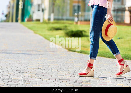 cropped image of stylish woman in jeans holding straw hat at street Stock Photo