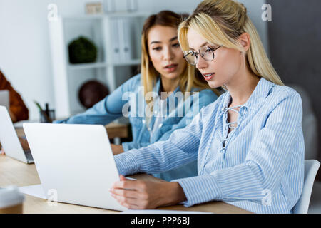 multicultural colleagues working on startup project in office and looking at laptop Stock Photo