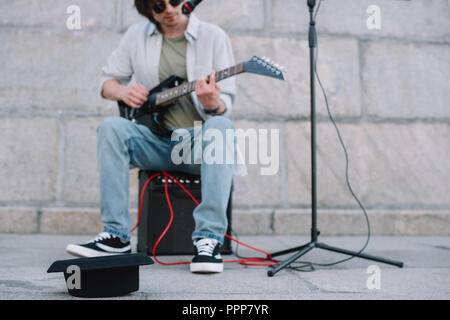 Empty hat in front of busker playing guitar and singing in urban environment Stock Photo