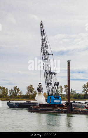 Floating crane and barge dredging the Steveston waterway near Vancouver Stock Photo