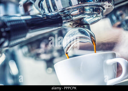 Close-up coffee machine pouring hot espresso in to white cup. Stock Photo