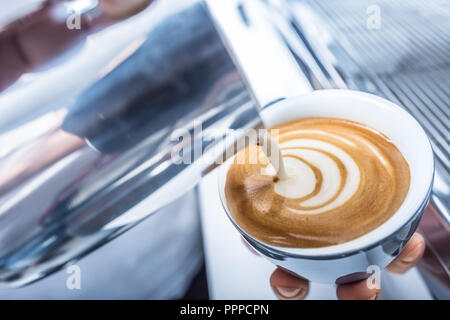 Barista making art coffee and pouring milk in to cup. Stock Photo