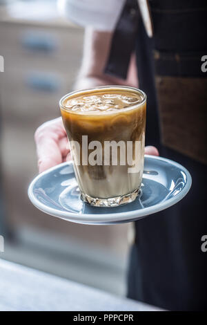Barista in coffee shop holding in her hand cup with ice coffee. Stock Photo