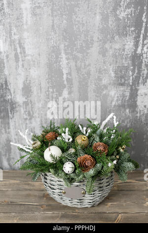 Preparation for holidays concept. Flower shop is a master work of a professional florist. Beautiful Christmas composition in a wicker basket on wooden boards. Stock Photo