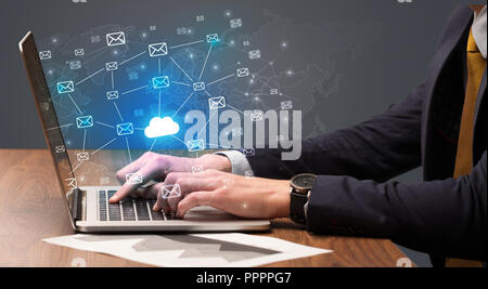Businessman hand sending a bunch of messages on laptop with cloud Businessman hand sending a bunch of messages on laptop with cloud
