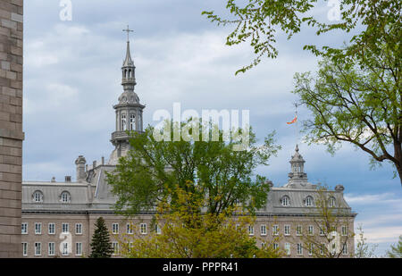 The Camille-Roy Building of the Séminaire de Québec behing trees at springtime. The ornamental steeple rises above the mansard roof. Quebec City Stock Photo