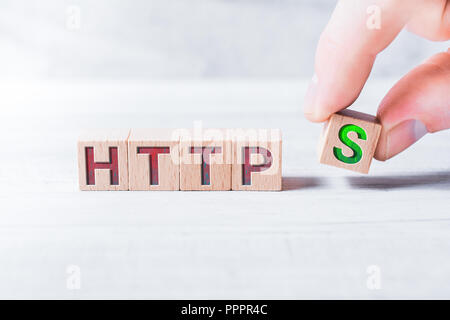 The Word HTTPS Formed By Wooden Blocks And Arranged By Male Fingers On A White Table Stock Photo