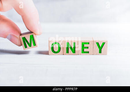 The Word Money Formed By Wooden Blocks And Arranged By Male Fingers On A White Table Stock Photo