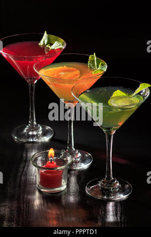 Kiwi, orange and cherry jelly with lime pieces in the glasses topped mint leaves with candle on the black background Stock Photo