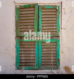 Old grunge window with closed green shutters on dirty bricks stone wall, Cairo, Egypt Stock Photo