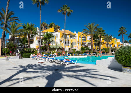 Apartments los mangos, palm trees, people by the swimming pool, blue sky and hot weather, roquetas de mar, almeria, spain Stock Photo