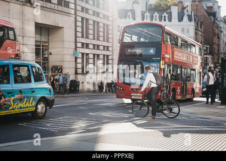 London, UK - September 17, 2018: Businessman on a bicycle waiting for traffic to pass on a street in the City of London, London, UK, London's famous f Stock Photo