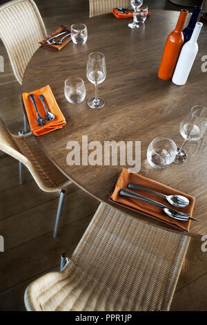 Modern cutlery and glasses on a wooden table in a restaurant Stock Photo