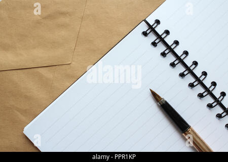 a notebook with clean sheets, an envelope and a gold pen on the table Stock Photo