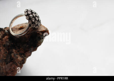 silver ring with precious stones on a stone, marble background Stock Photo