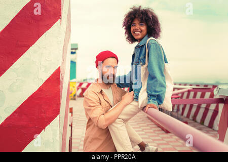 Handsome man looking confident while his girlfriend sitting on the hand rail Stock Photo