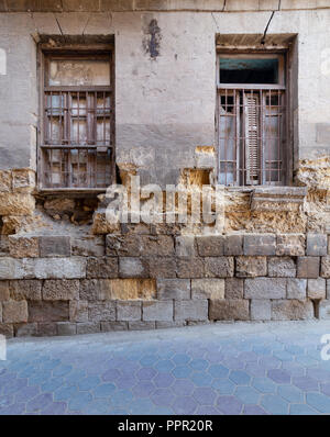 Two adjacent broken windows and grunge stone bricks wall in abandoned Darb El Labana district, Cairo, Egypt Stock Photo