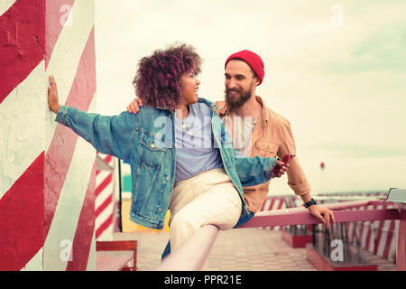 Attractive young girl turning to her boyfriend while sitting on the hand rail Stock Photo