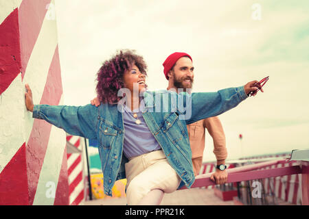Excited woman pointing to the distance while sitting near her boyfriend Stock Photo