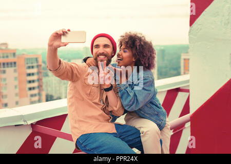 Funny young couple making ridiculous faces while taking selfies together Stock Photo